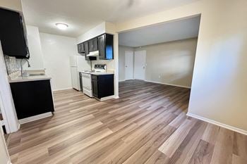 A renovated living room and kitchen with wood flooring 